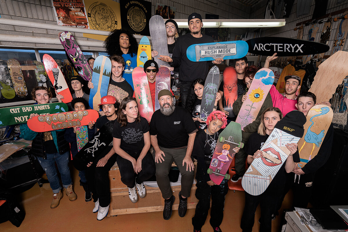 Students holding skateboards in alternative high school classroom