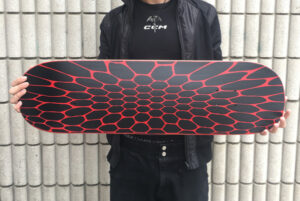 Photo of student holding a skateboard with graphic artwork on it.