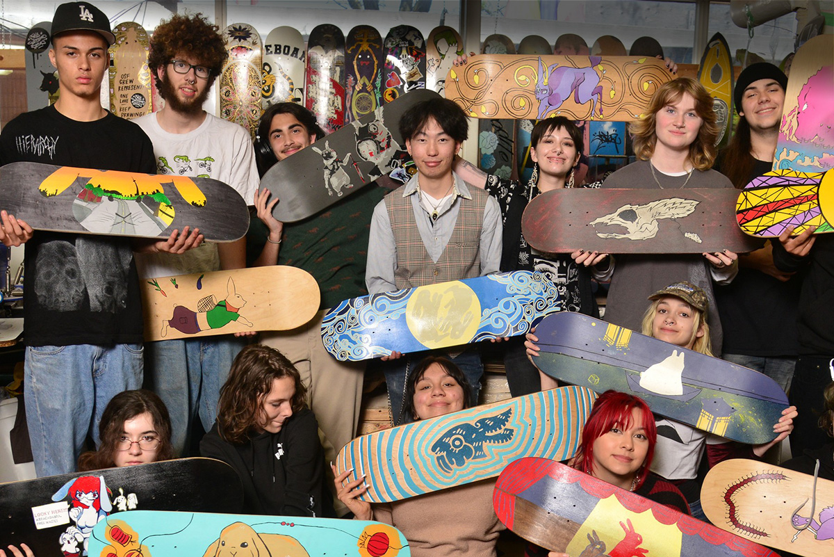 Photo of students in class holding skateboards