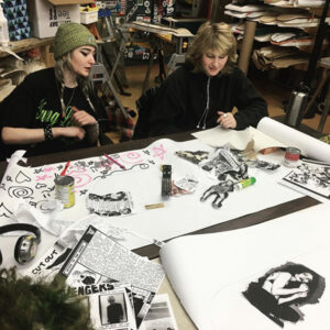 Photo of 2 students in a classroom working on an art project